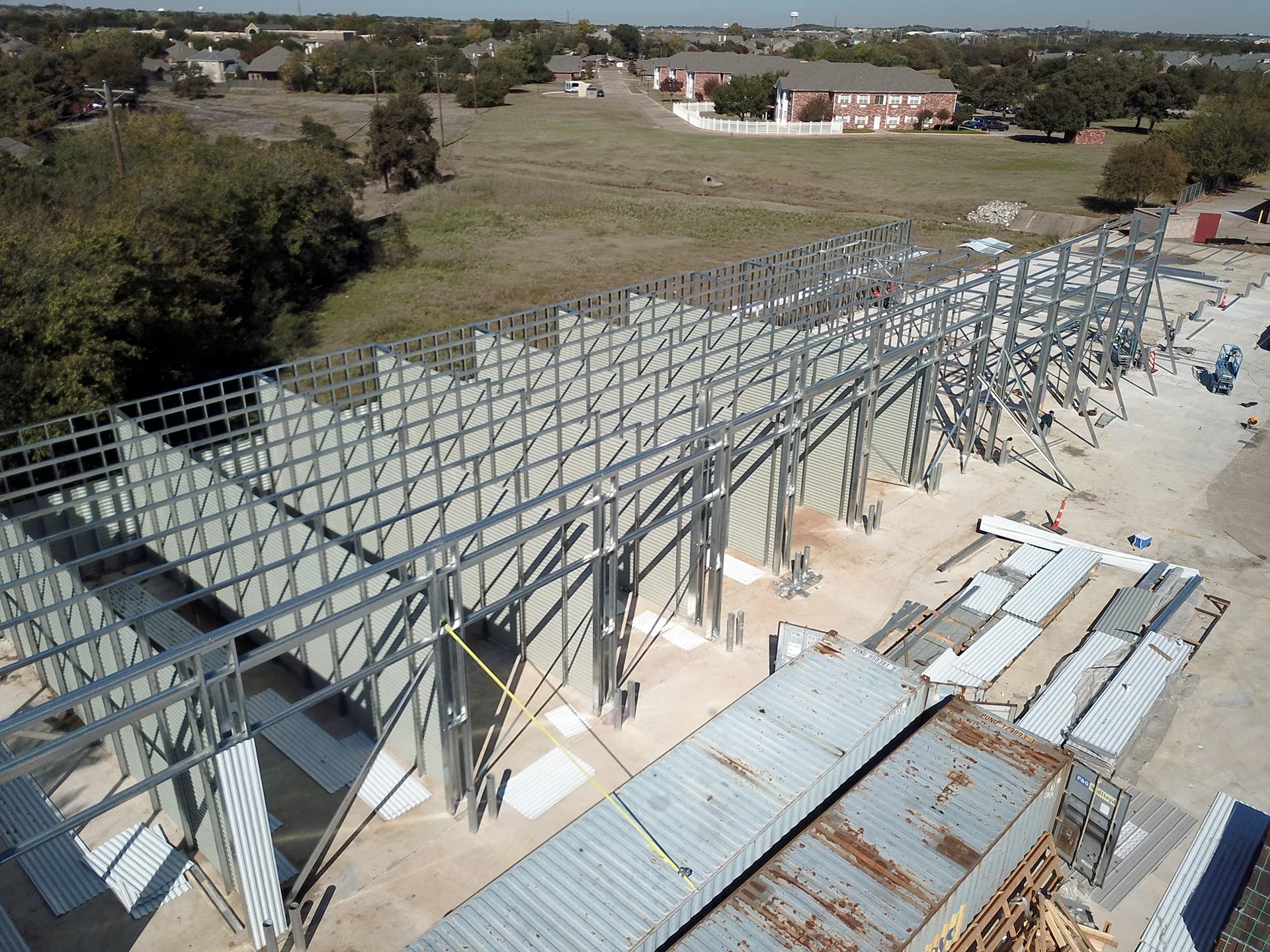Aerial view of a completed metal building on a cleared Texas site with gravel drive and surrounding acreage