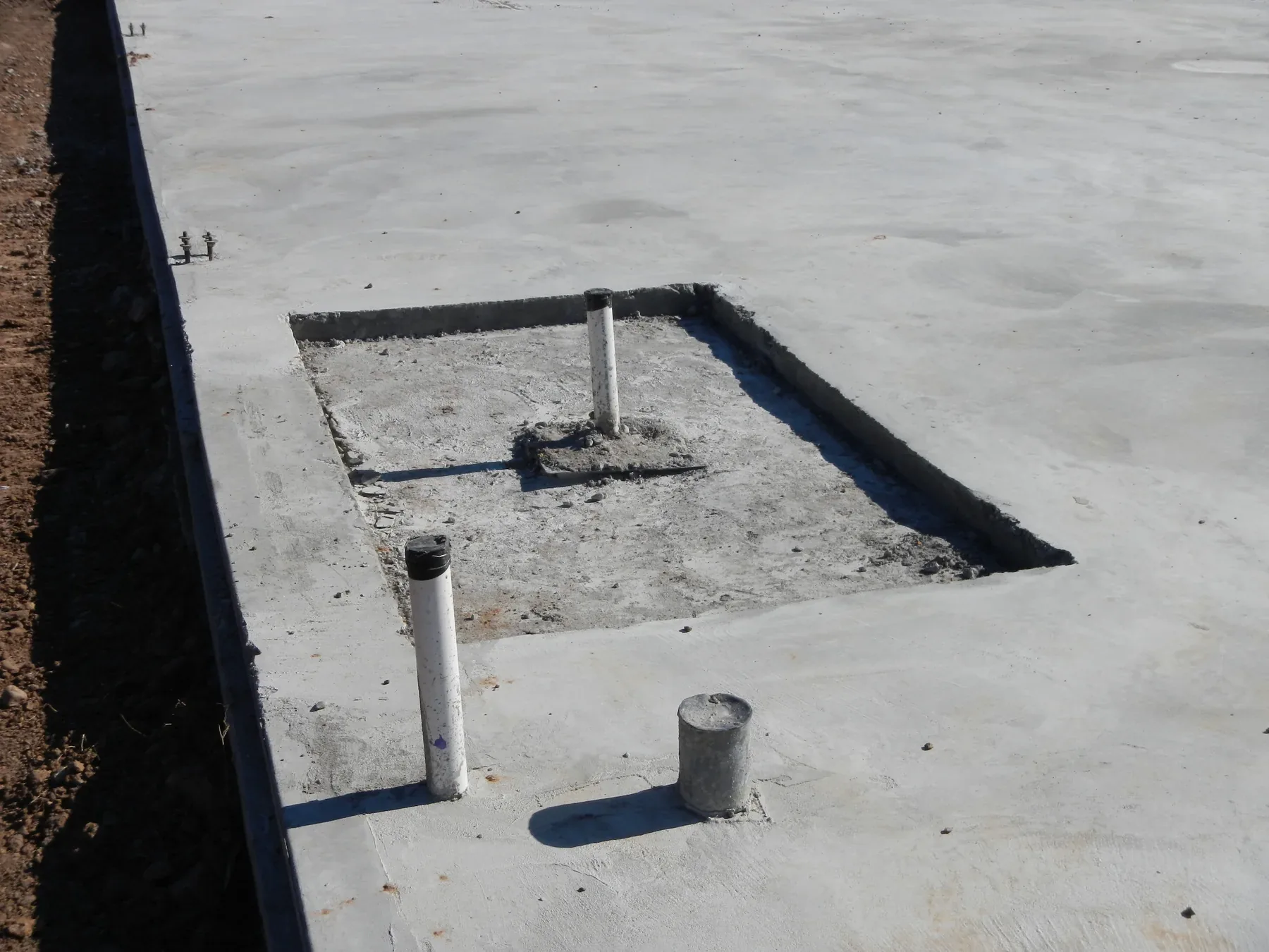 Anchor bolt assembly cast into a concrete pier pocket at the edge of a building slab
