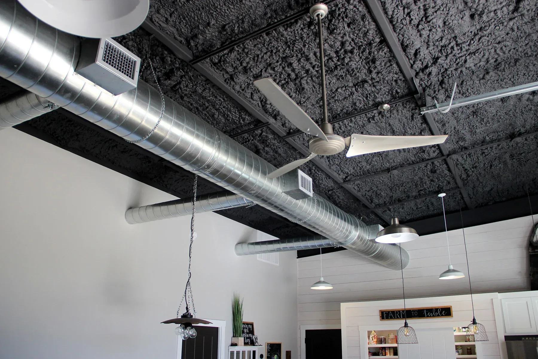 Barndominium interior with exposed ductwork and ceiling fans under a high open ceiling