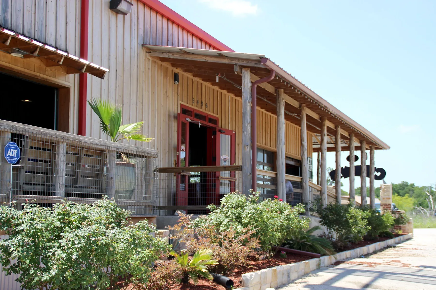 Covered porch running along the side of a commercial metal building with timber posts and a red roof