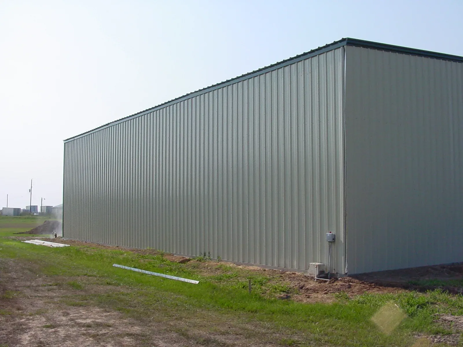 Long grey metal warehouse with a clean unbroken sidewall running back from the corner
